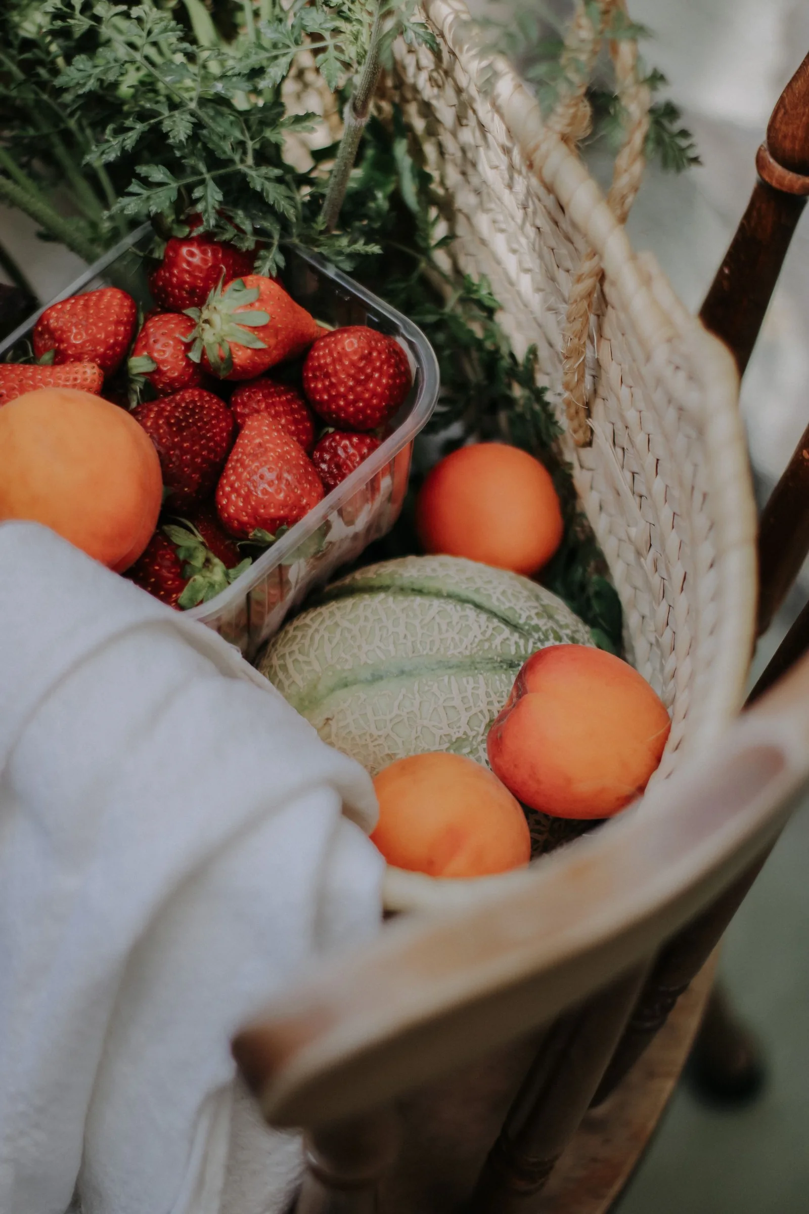 Strawberries, peaches and a melon in a woven basket